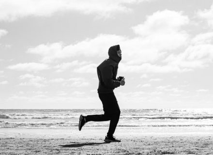 Silhouette of a jogger running along La Lucila del Mar beach, captured in monochrome.